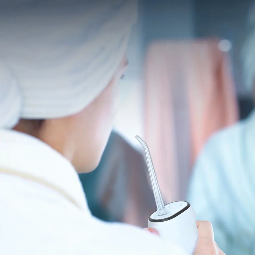 Woman using Grin Teeth WF 1 travel water flosser in daily bathroom routine