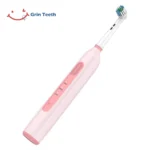 Grin Teeth ET 6A rotating oscillating electric toothbrush in pink, tilted front view showing 3 brushing modes and quiet round brush head