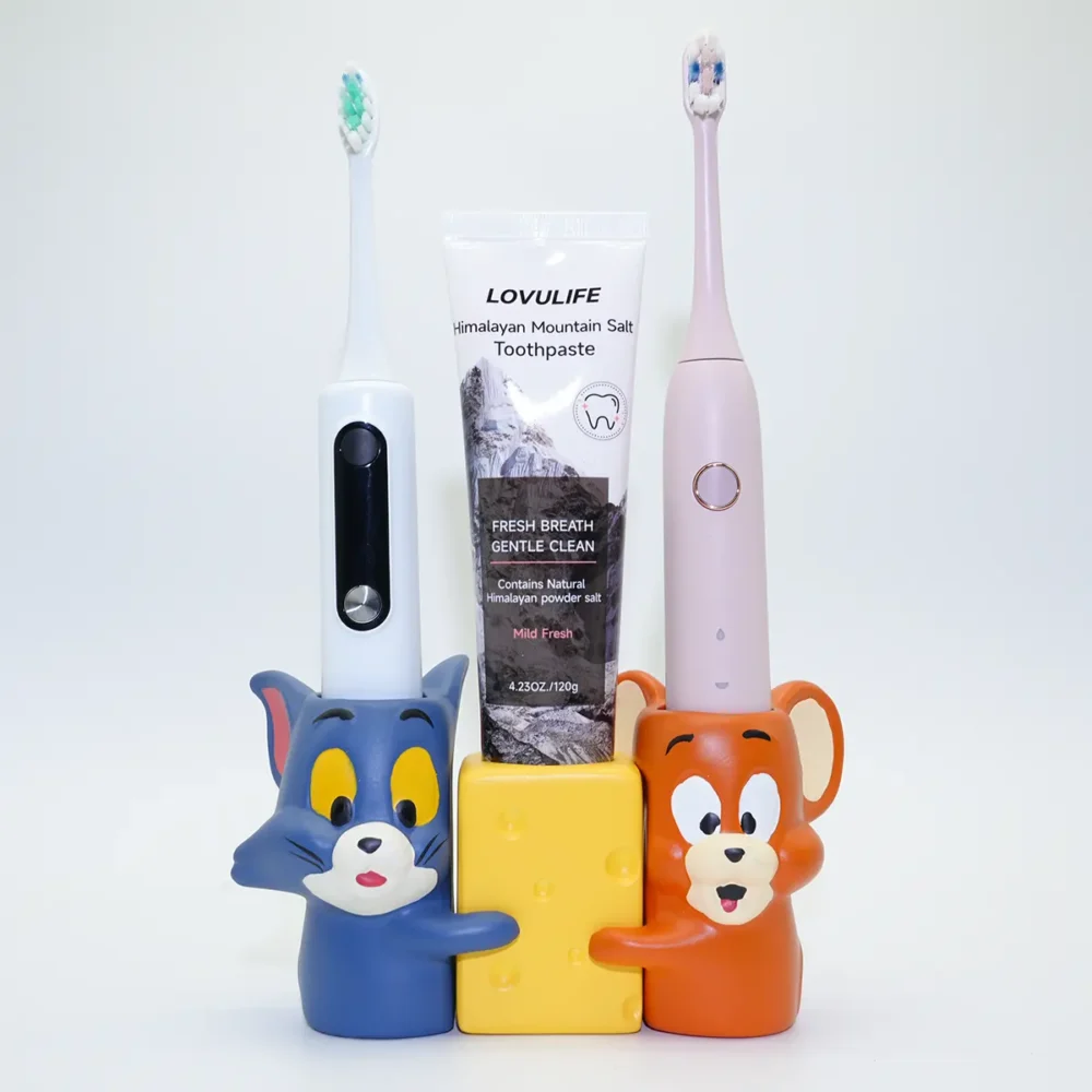 Tom and Jerry ceramic toothbrush holders holding electric toothbrushes and toothpaste, styled for couple bathroom use