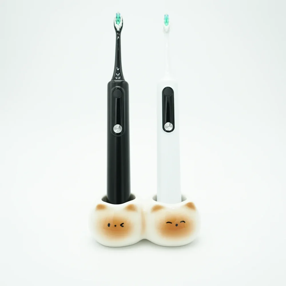 Ceramic cute toothbrush holder with 2 slots holding black and white electric toothbrushes