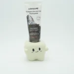 Tooth-shaped ceramic toothbrush holder storing a tube of toothpaste