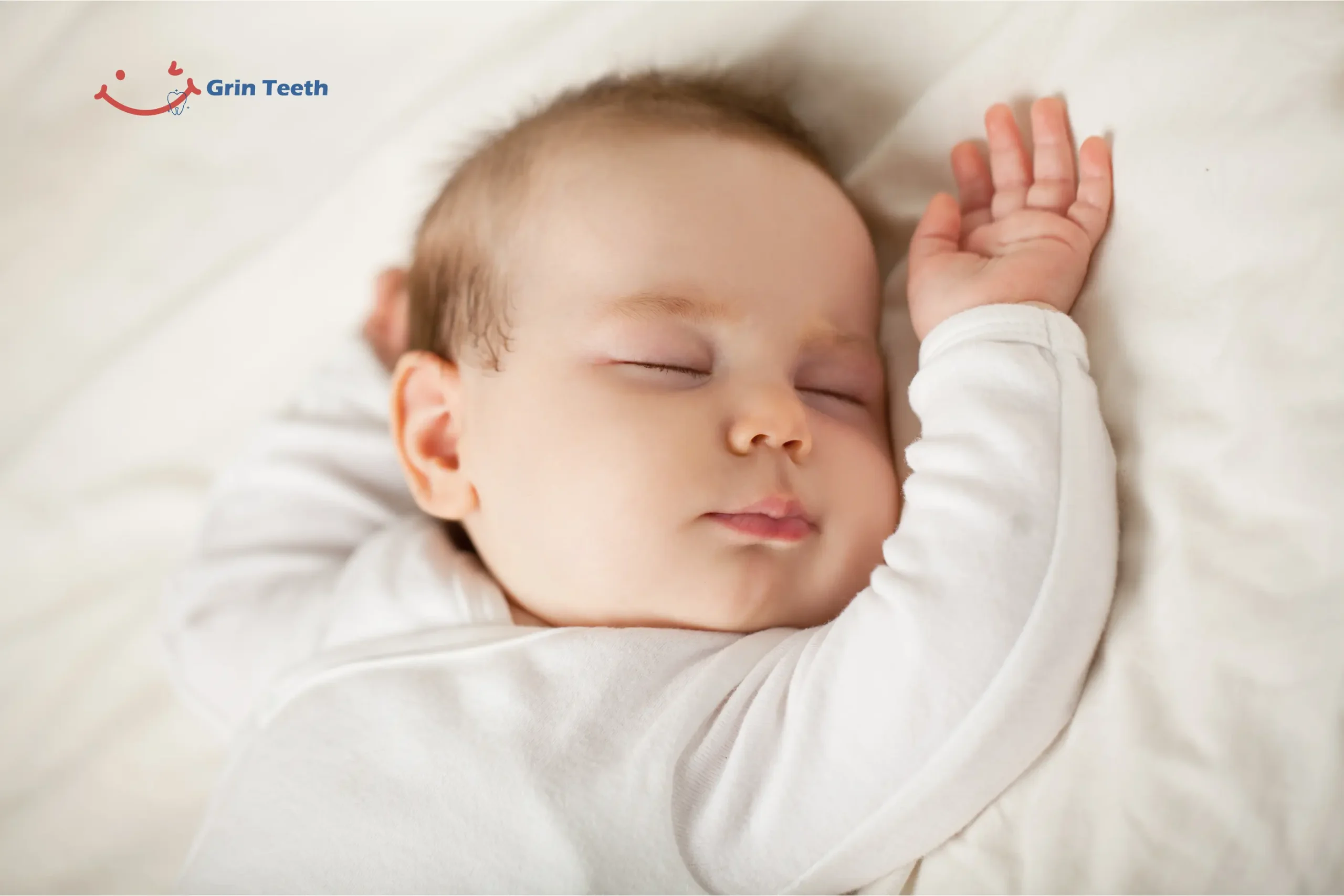 Sleeping baby on white bedding with arm raised—do babies sleep more when teething? Calm, restful image for teething-sleep guide.