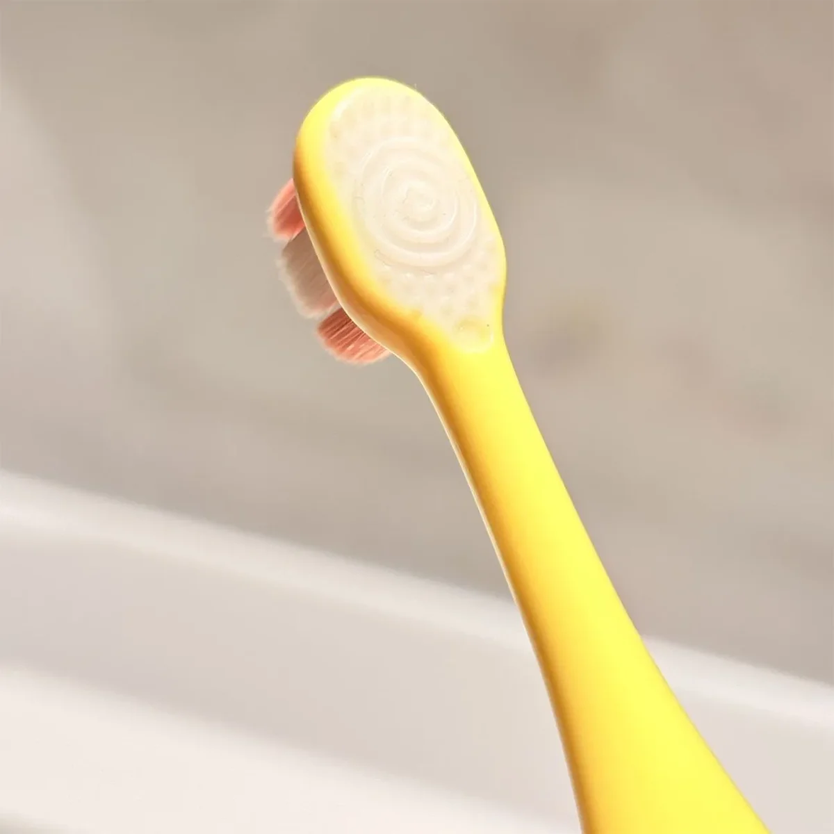 Donut Toddler Toothbrush KT 3 Soft Head Detail Close-up of Grin Teeth KT 3 donut toddler toothbrush—yellow handle, extra-soft bristles, rounded head with spiral silicone tongue cleaner