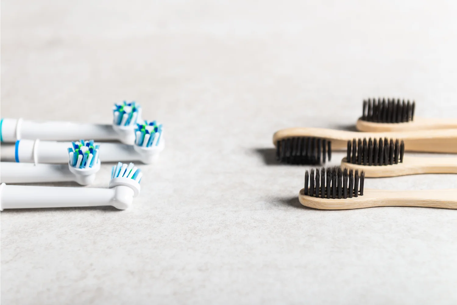 Grin Teeth About Us – Electric vs Bamboo Toothbrushes Grin Teeth About Us image: electric toothbrush heads facing bamboo manual toothbrushes on a light surface