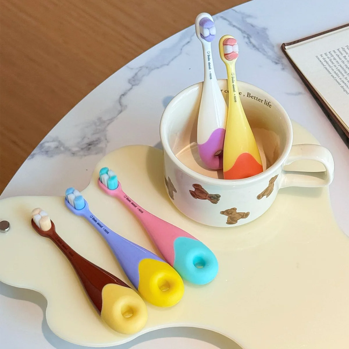 Order Donut Toddler Toothbrush KT 3 Soft Non Five Grin Teeth KT 3 donut toddler toothbrushes in and beside a cup on tabletop; extra-soft bristles, toddler-size donut handles