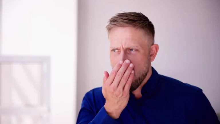 Tooth decay cause bad breath—man covering his mouth, checking odor; concept image of cavities trapping food and bacteria (VSCs).